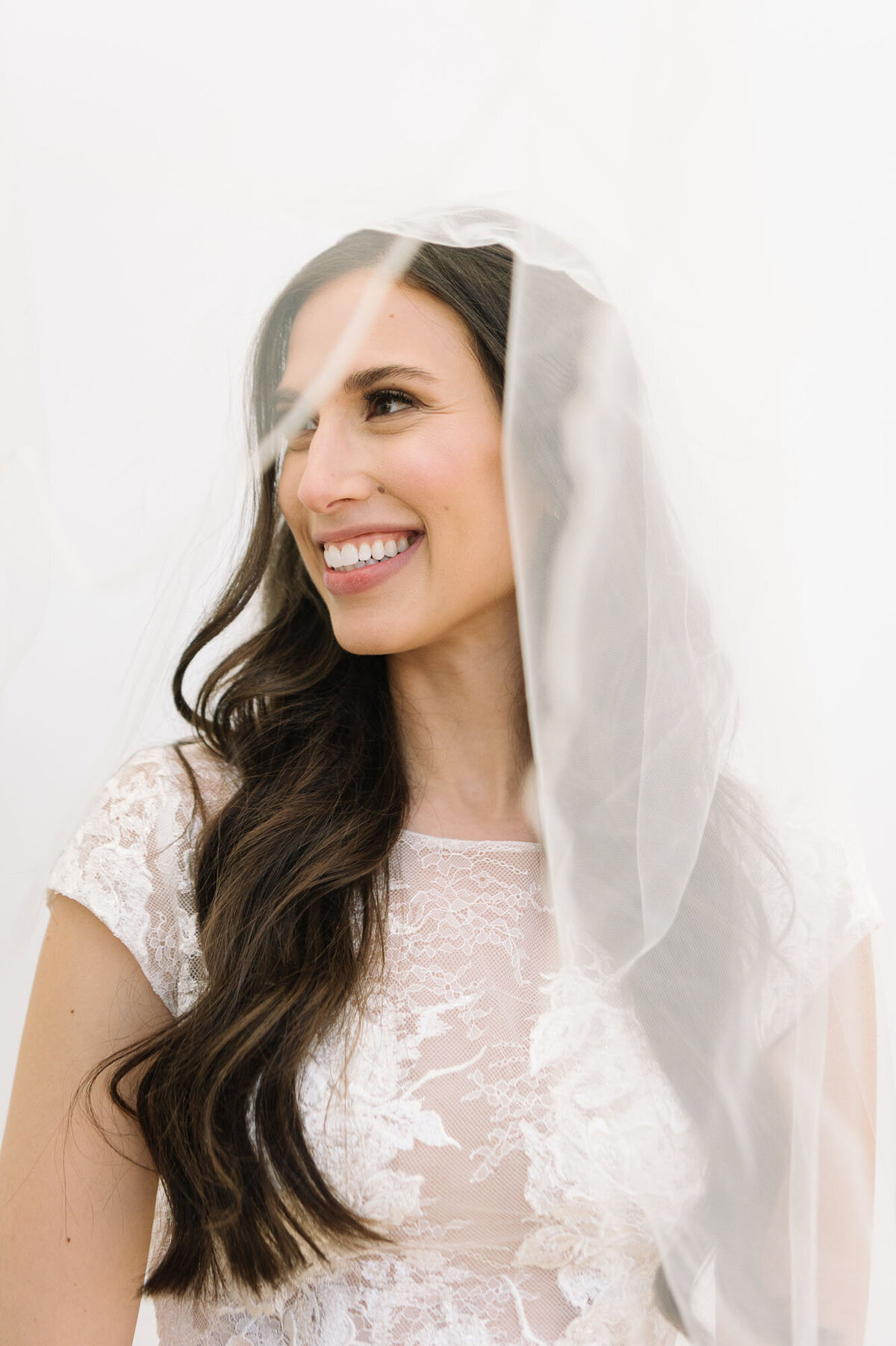 A beautiful bride looks to the side as her veil falls over her shoulder.