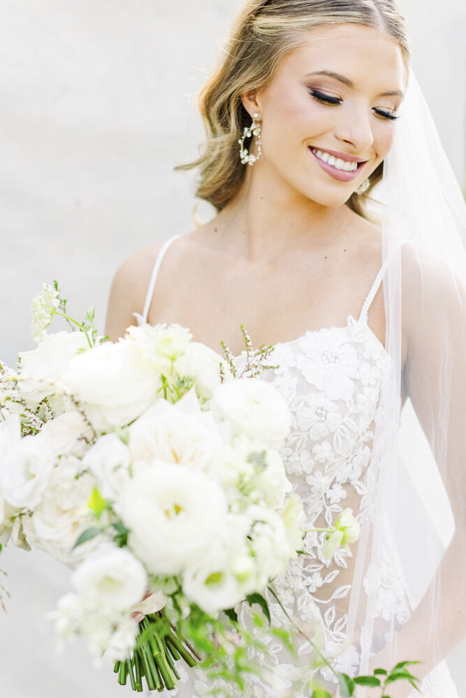 bride smiling and holding a white flower bouquet