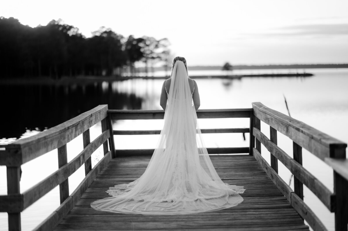 bride standing at the end of a dock on a lake