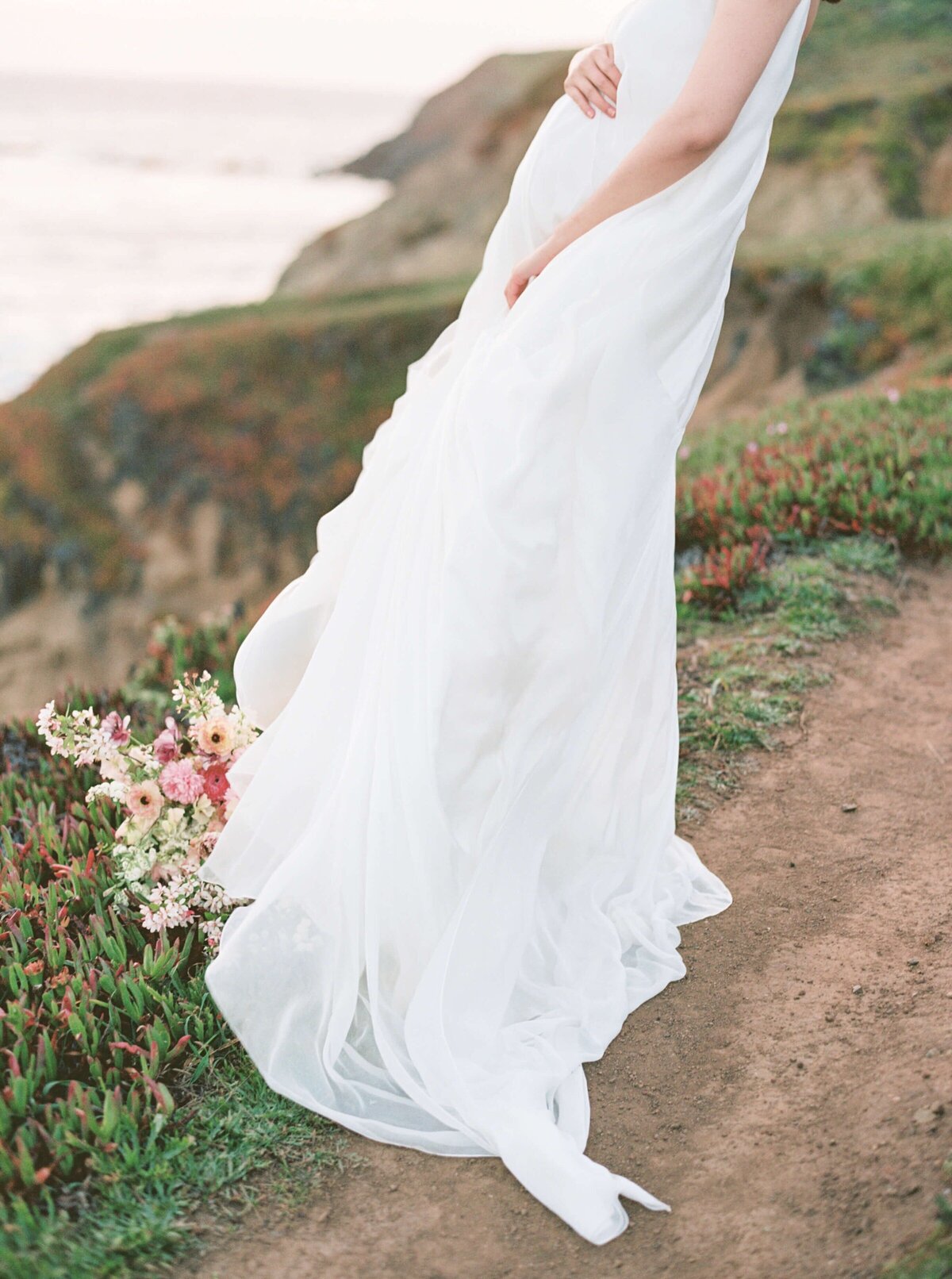 San Francisco maternity photography session on the coast with a woman wearing a white dress with a bouquet