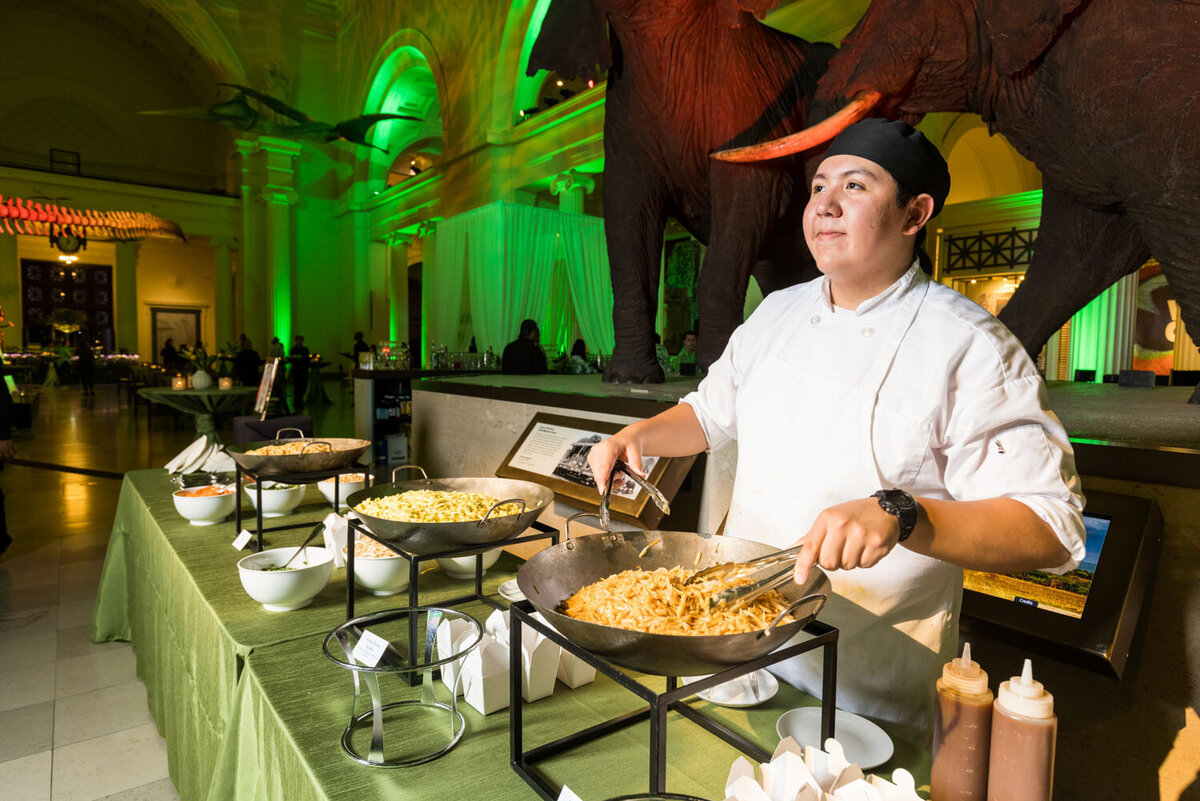 Chef preparing pasta at buffet in museum setting