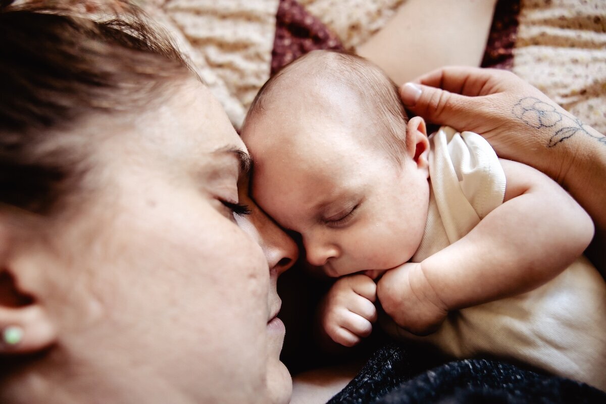 a newborn baby girl fast asleep next to her mom