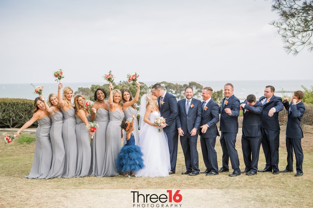 Wedding party cheers as the Bride and Groom share a kiss