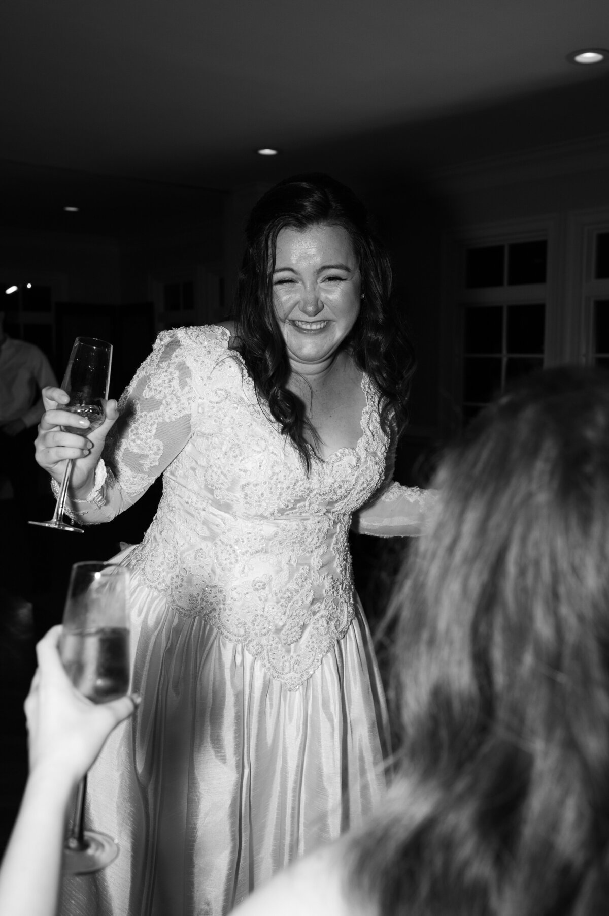 A bride laughing and dancing with guests at a wedding reception