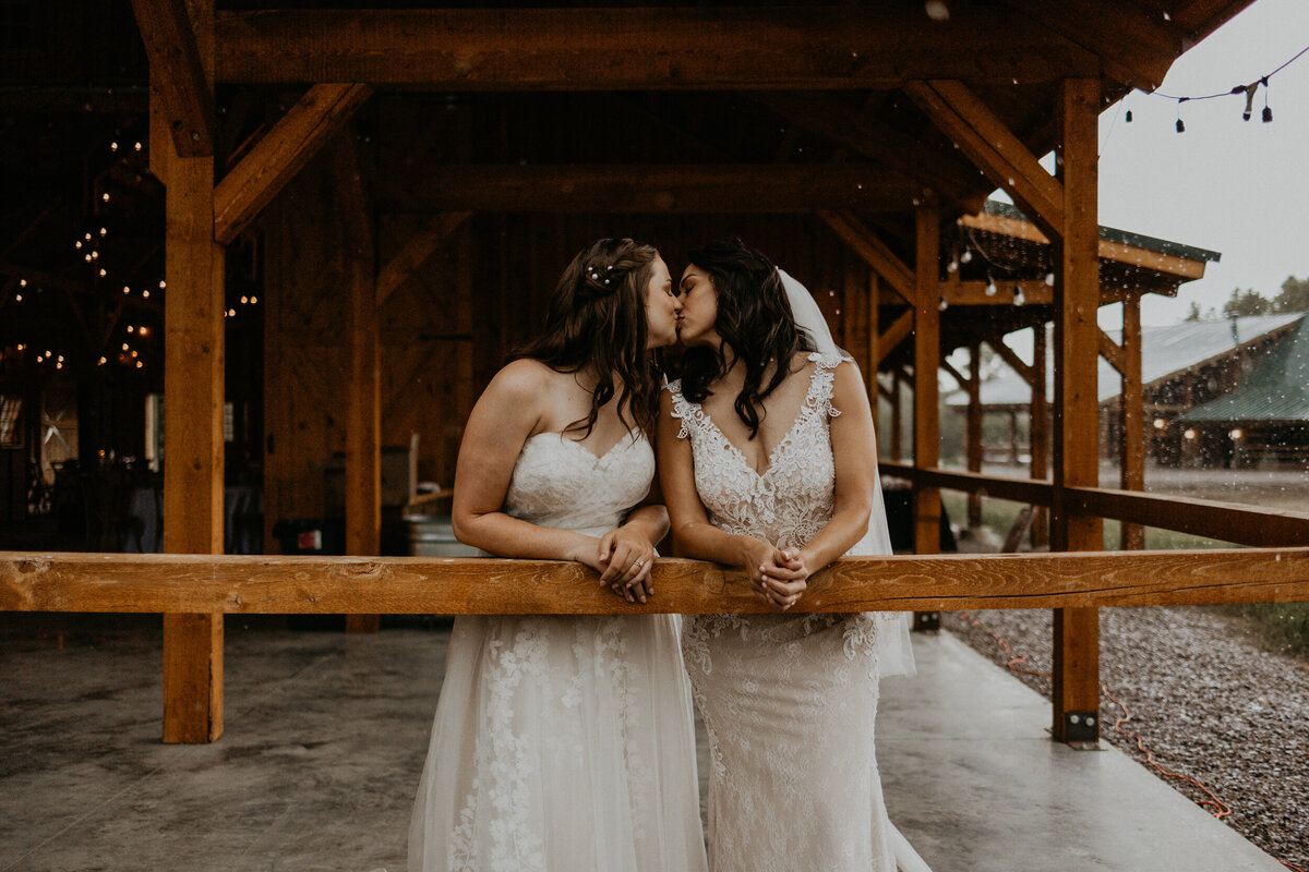 two brides playing in the rain in their wedding dresses