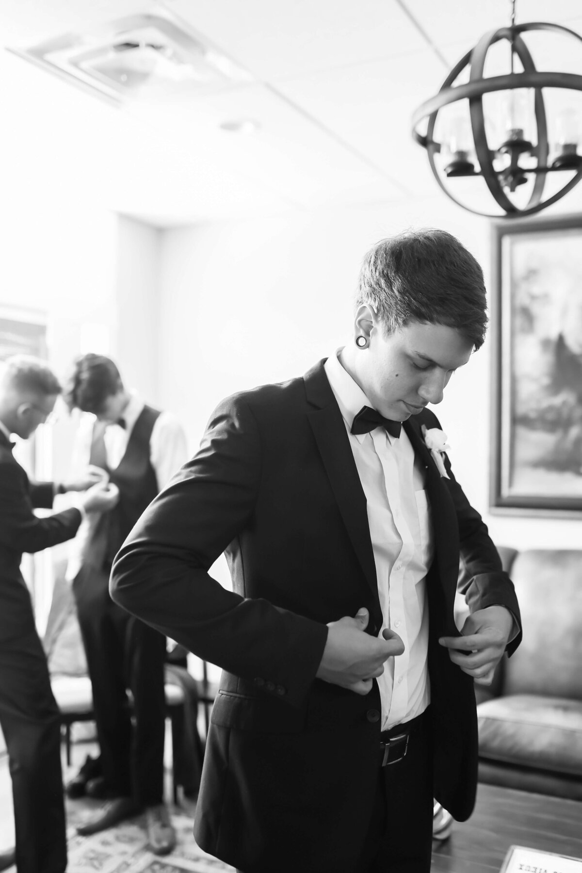 Groom putting his suit on for wedding at  Ruby Cora wedding venue in Clarksville, TB