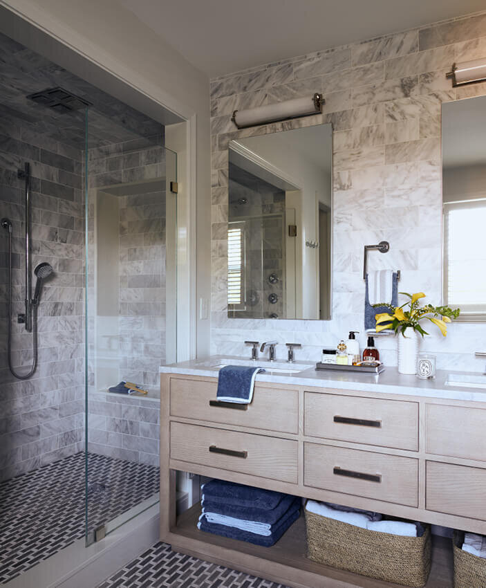 Hingham interior design creates a bathroom with a natural oak vanity and marble tile, blending modern elements with timeless style for a refined space.