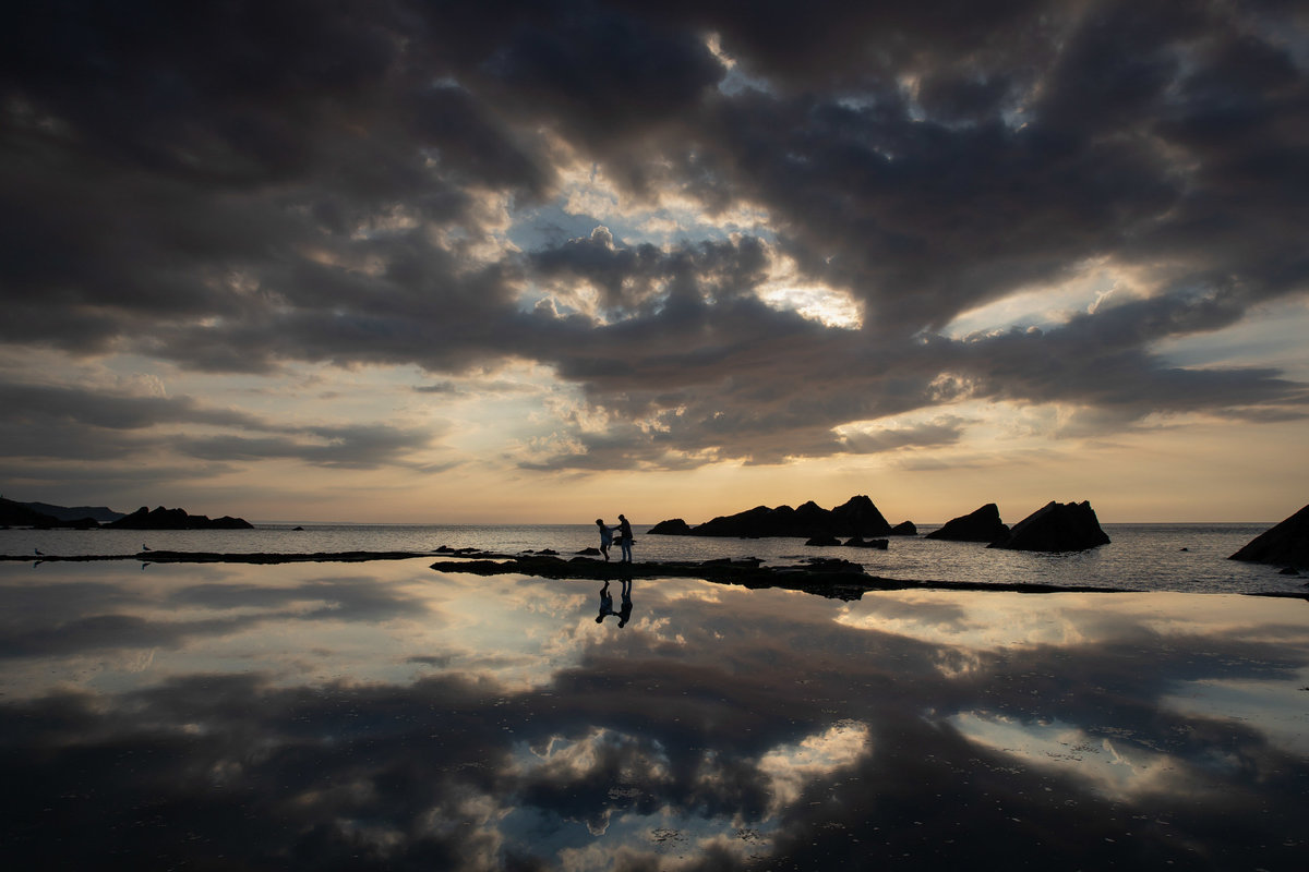 Silhouette sunset of couple walking in the tidal pools at Tunnels Beaches North Devon Wedding venue