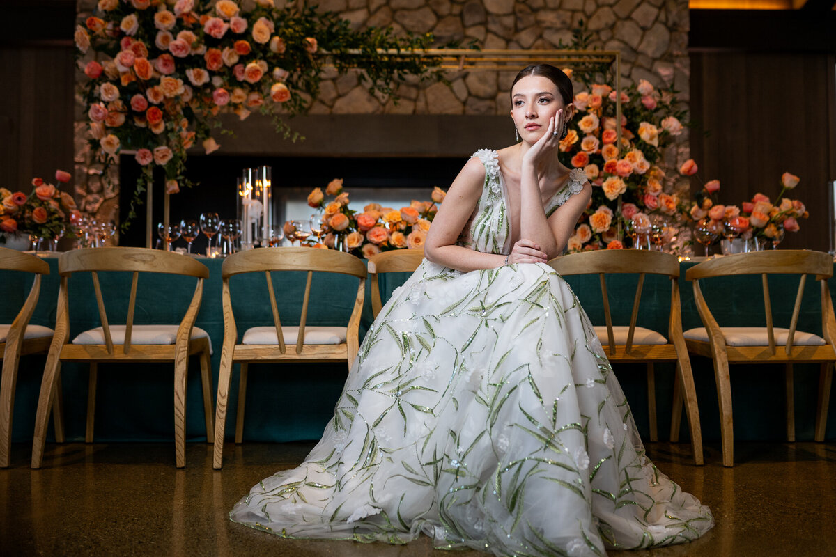 San Francisco Bay Area wedding photographer documents elegant bridal portrait with bride in botanical print gown against stone wall and vibrant orange floral backdrop at Estate Yountville in Napa Valley