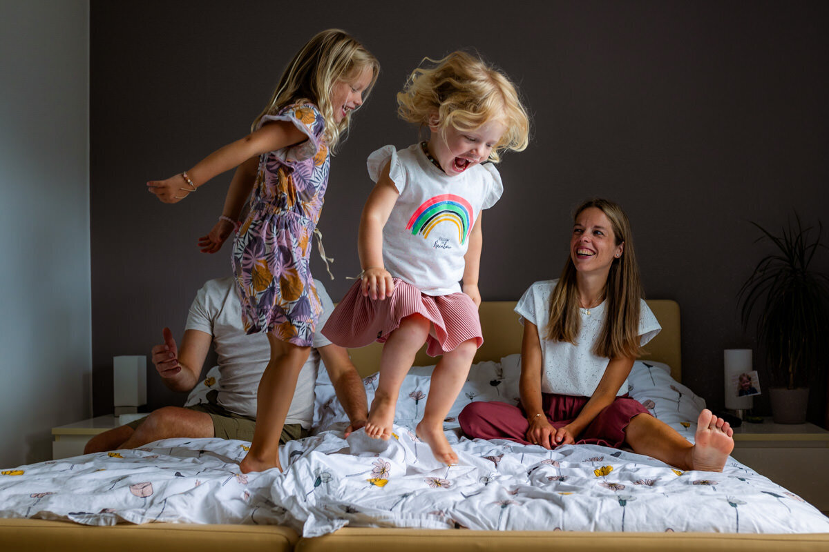 gezinsfoto aan huis springen op bed