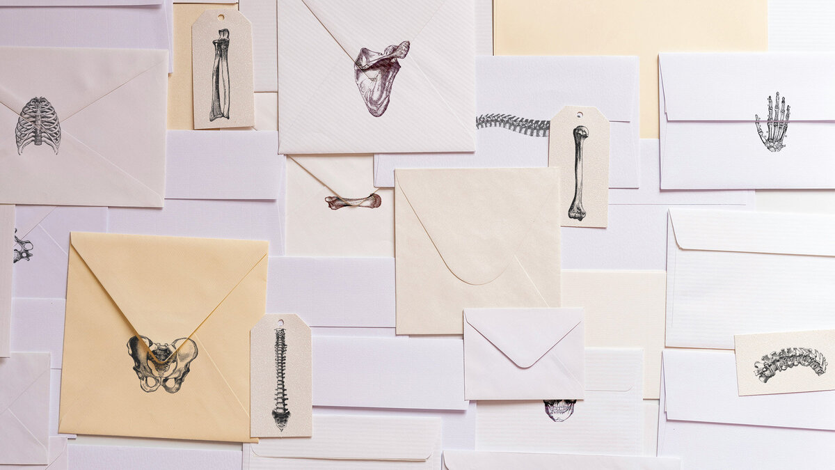 various envelopes spread across a table and overlapping each other stamped with drawings of bones from the human body
