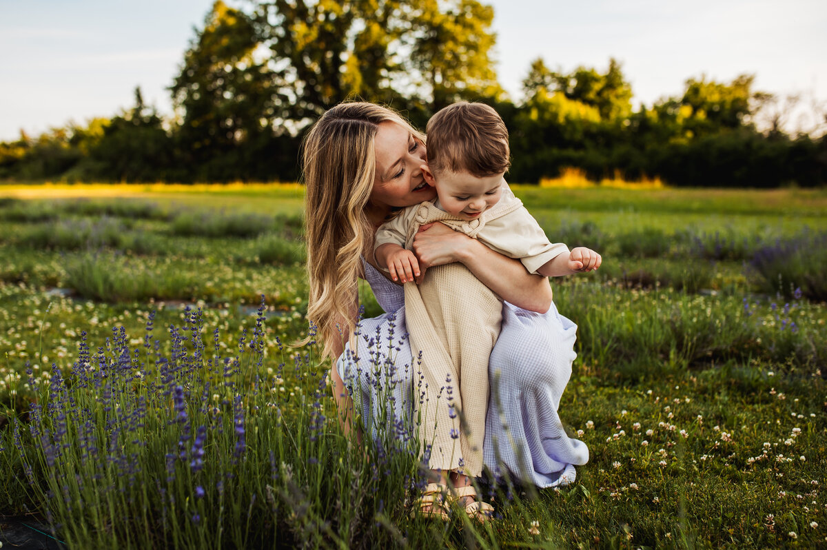 Mother holding her child in a lavender field during Ottawa mini session, joyful seasonal family photography.