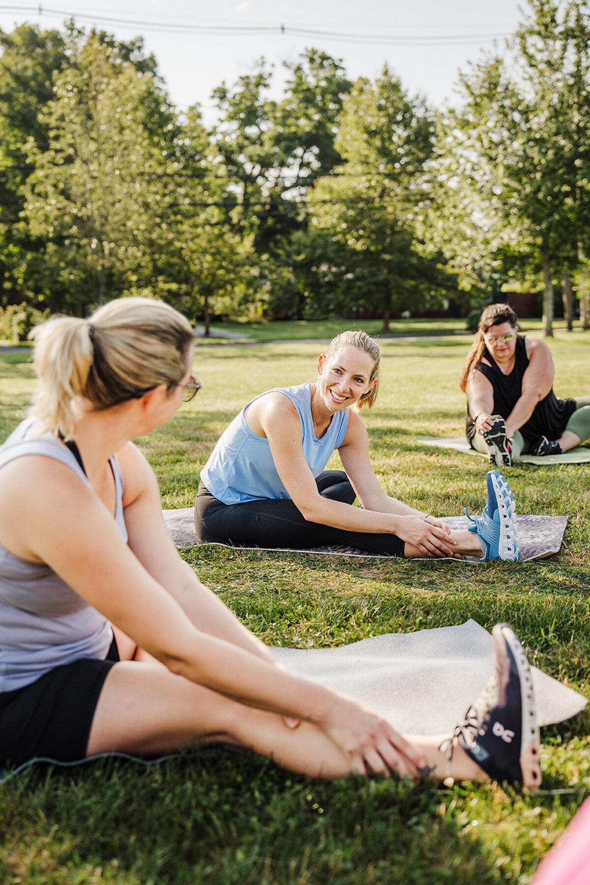 personal trainer instructs women during a workout class on grass