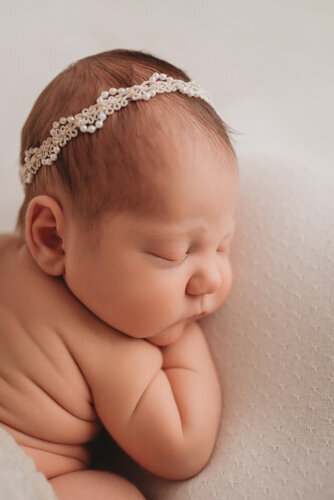 Baby girl sleeping for newborn portrait session with Atlanta Georgia newborn photographer snuggled up on her side on neutral fabric backdrop