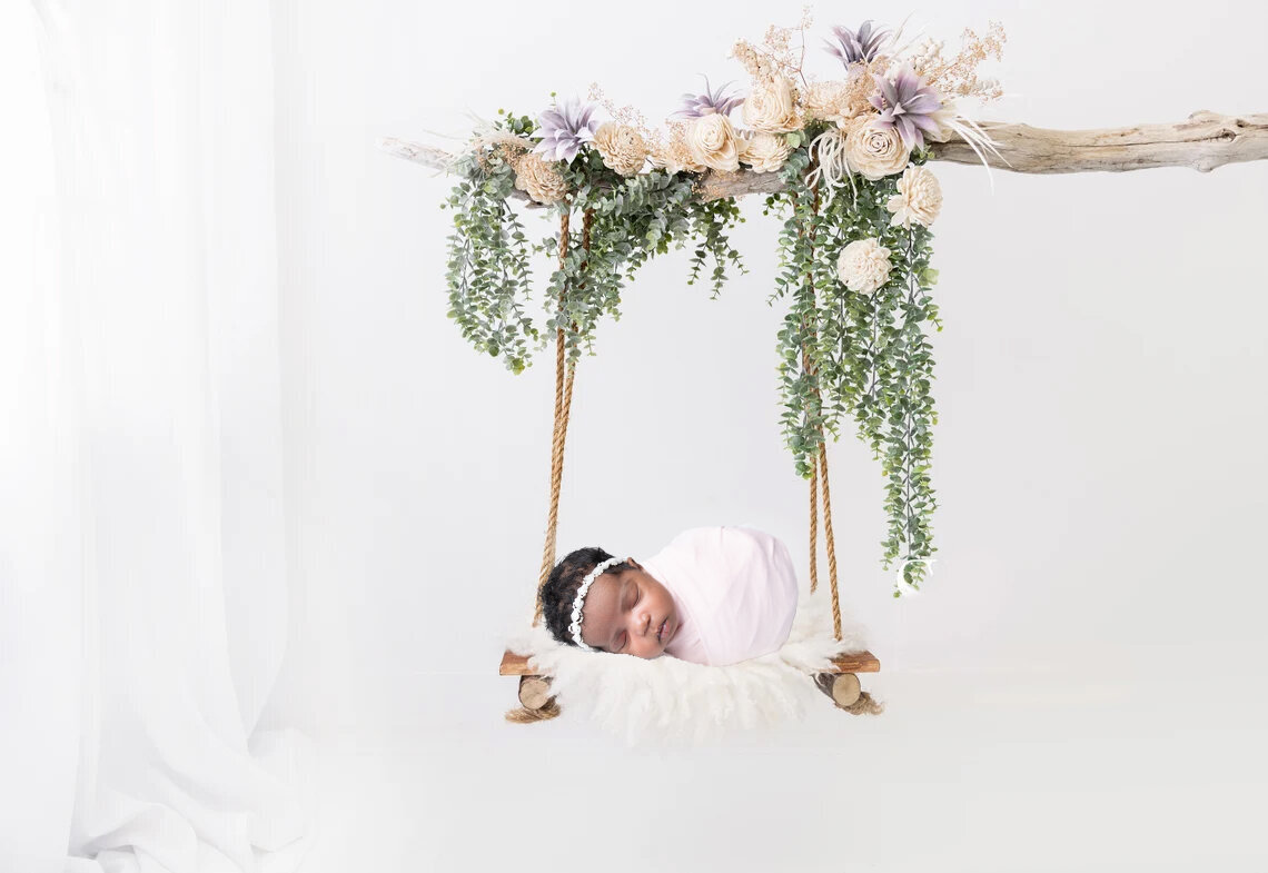 newborn baby girl in swing for session