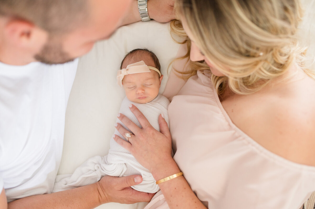 new parents snuggling baby on bed