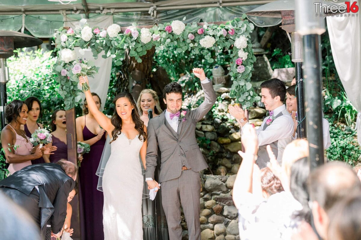 Bride and Groom walk down the aisle hand in hand and fists in the air of celebration