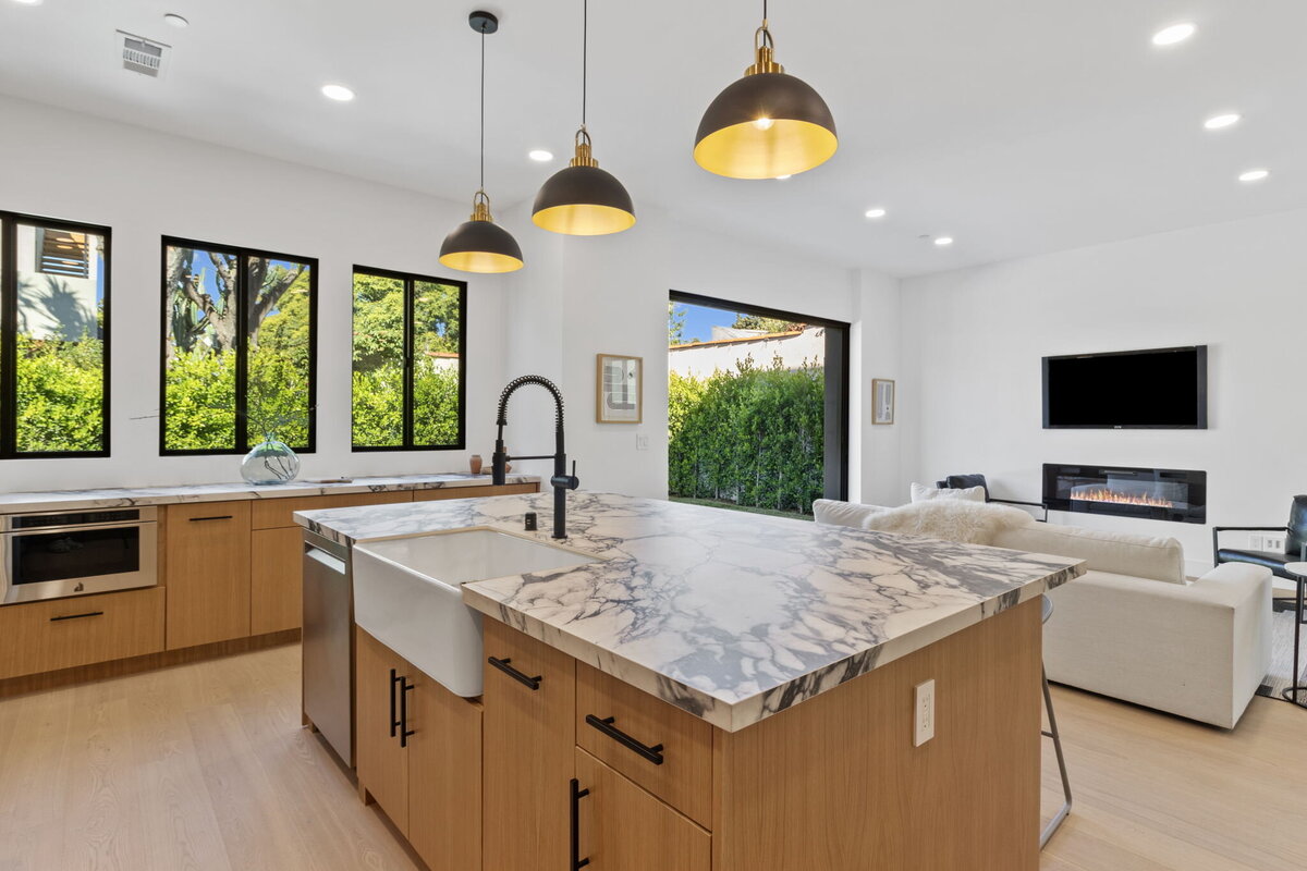 warm-wood-kitchen-with-marble-counters-and-modern-lighting