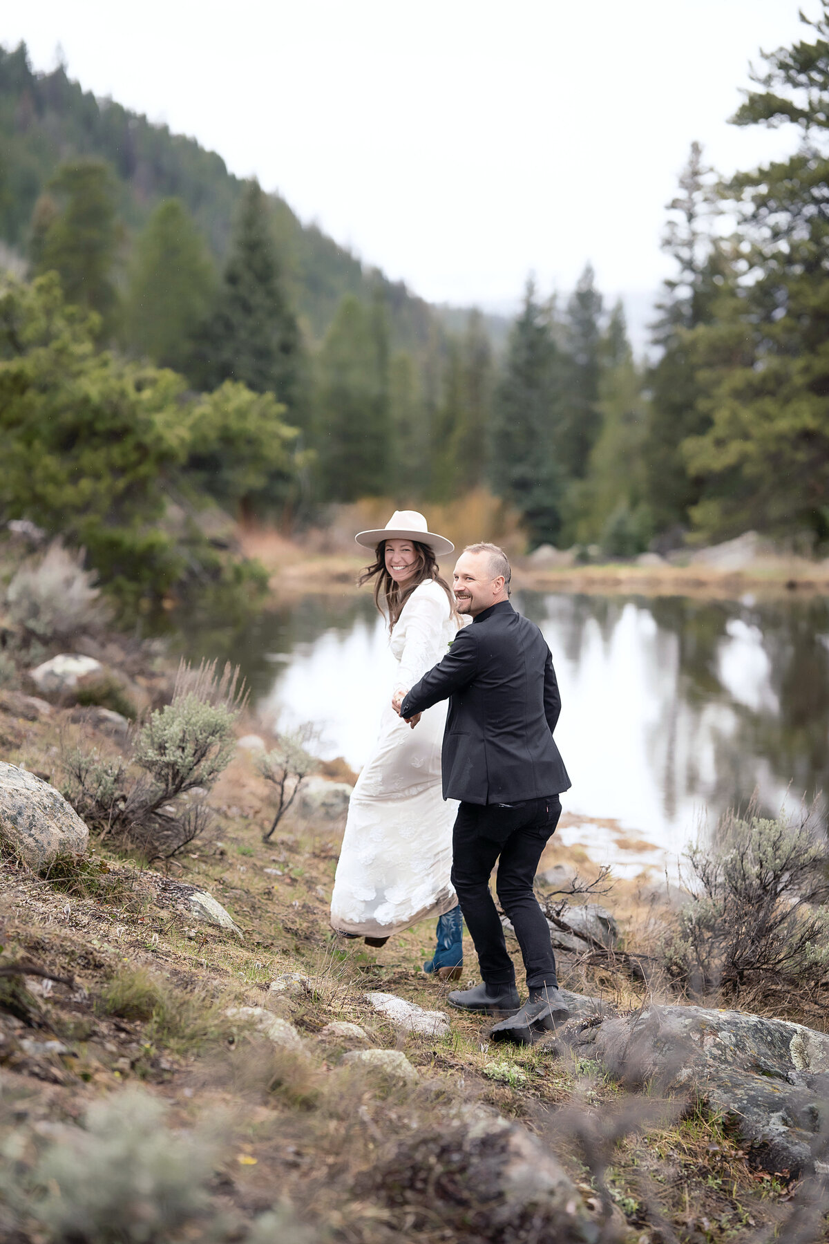 A beautiful bride grabs her grooms hand as pulls him along the beach, in their Aspen, Colorado wedding.