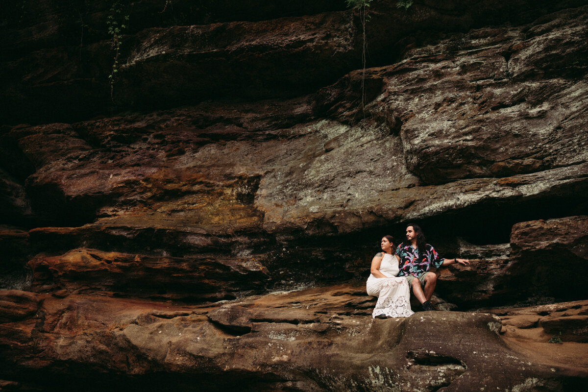 Couple sit on cave wall by Ohio elopement photographer Paige Mireles Photography