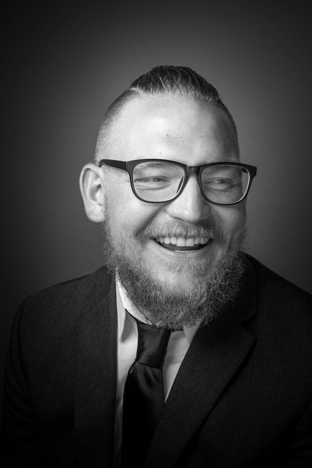 High-contrast black and white studio portrait of a man with an editorial style.