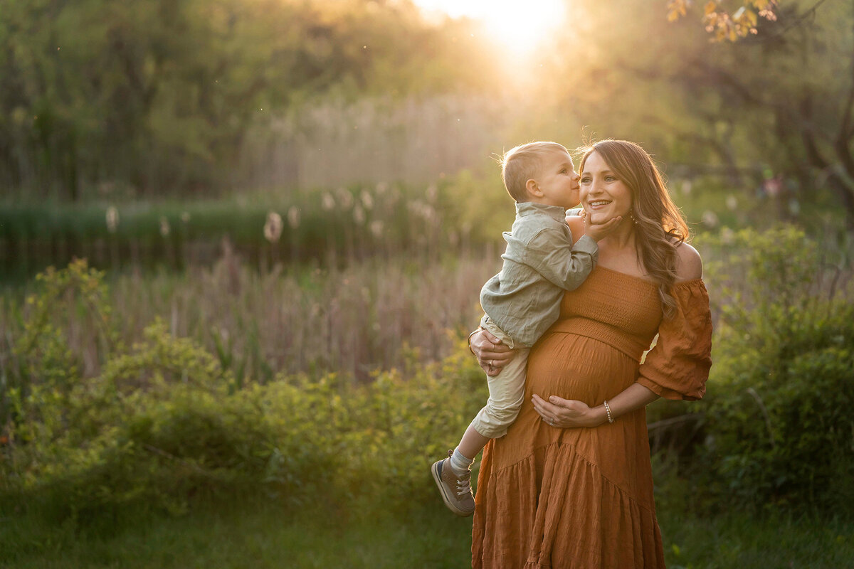 Little boy whispers a secret into his mom's ear during her NJ maternity session