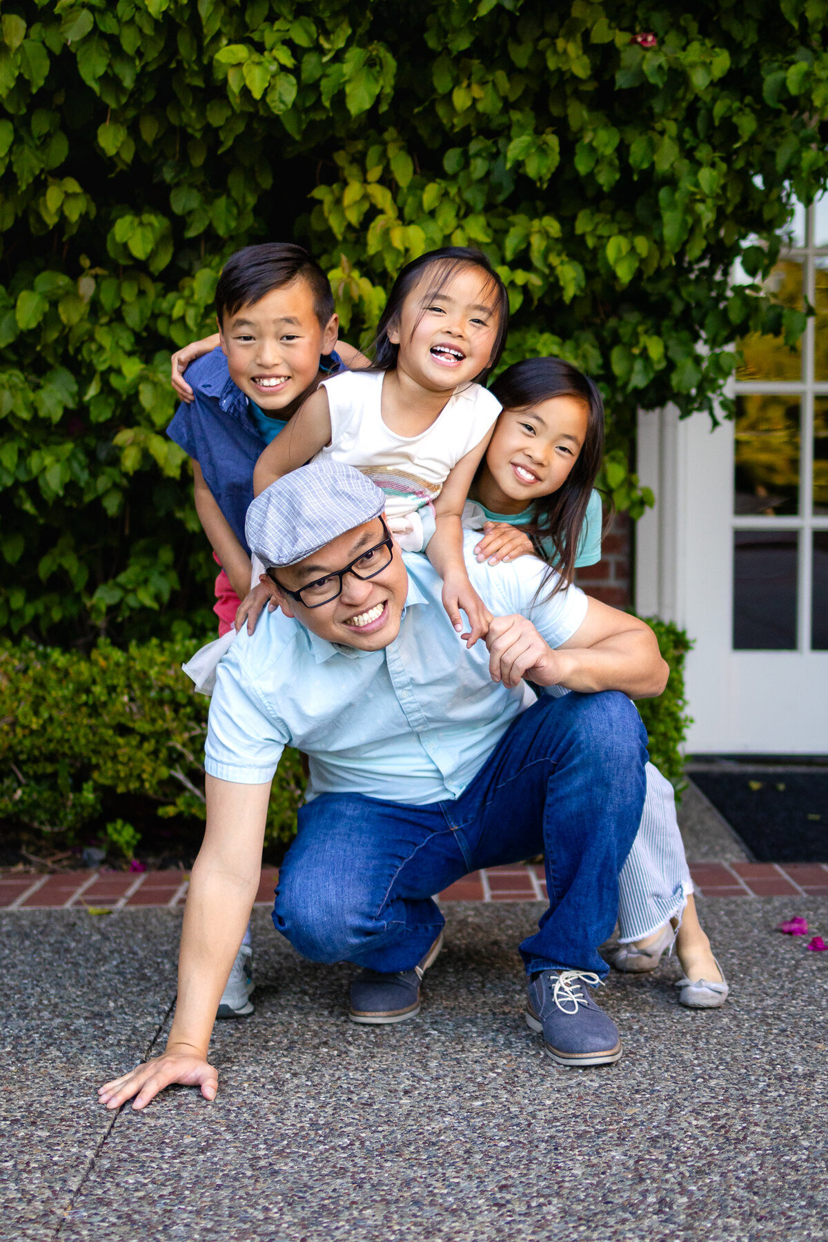 Smiling dad with three kids stacked playfully during Bay Area Family Portfolio session at Kohl Mansion Burlingame – Ellobelle Photography