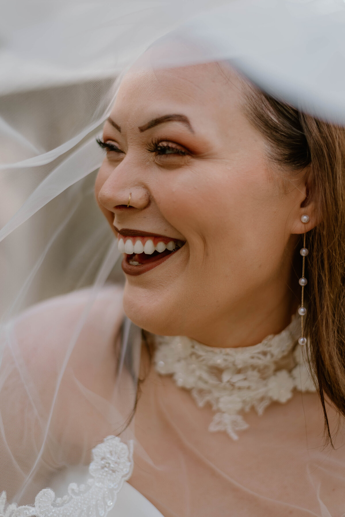 a bride laughing underneath her veil.