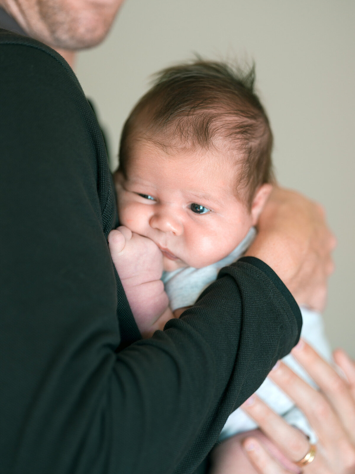 Newborn with chubby cheeks resting on father’s chest during natural in-home newborn photography session in Walnut Creek