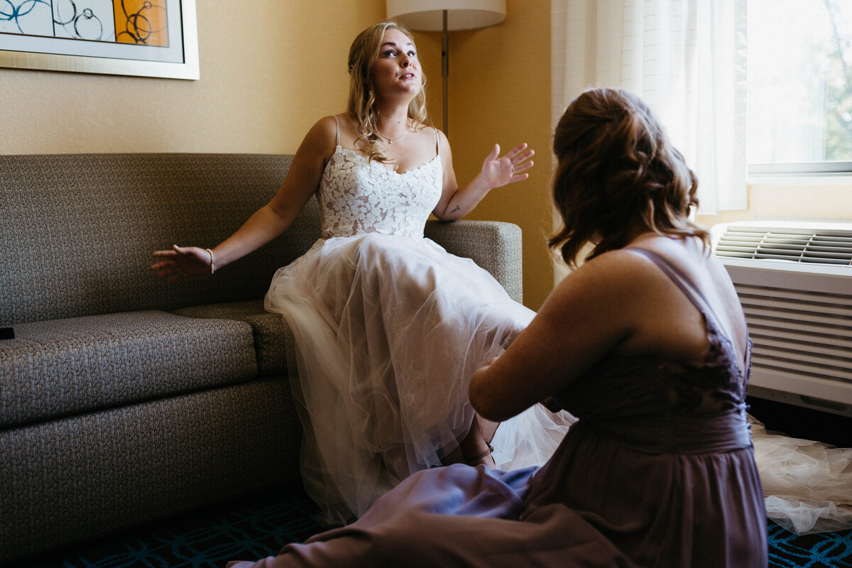 bridesmaid-helping-bride-get-shoes-on