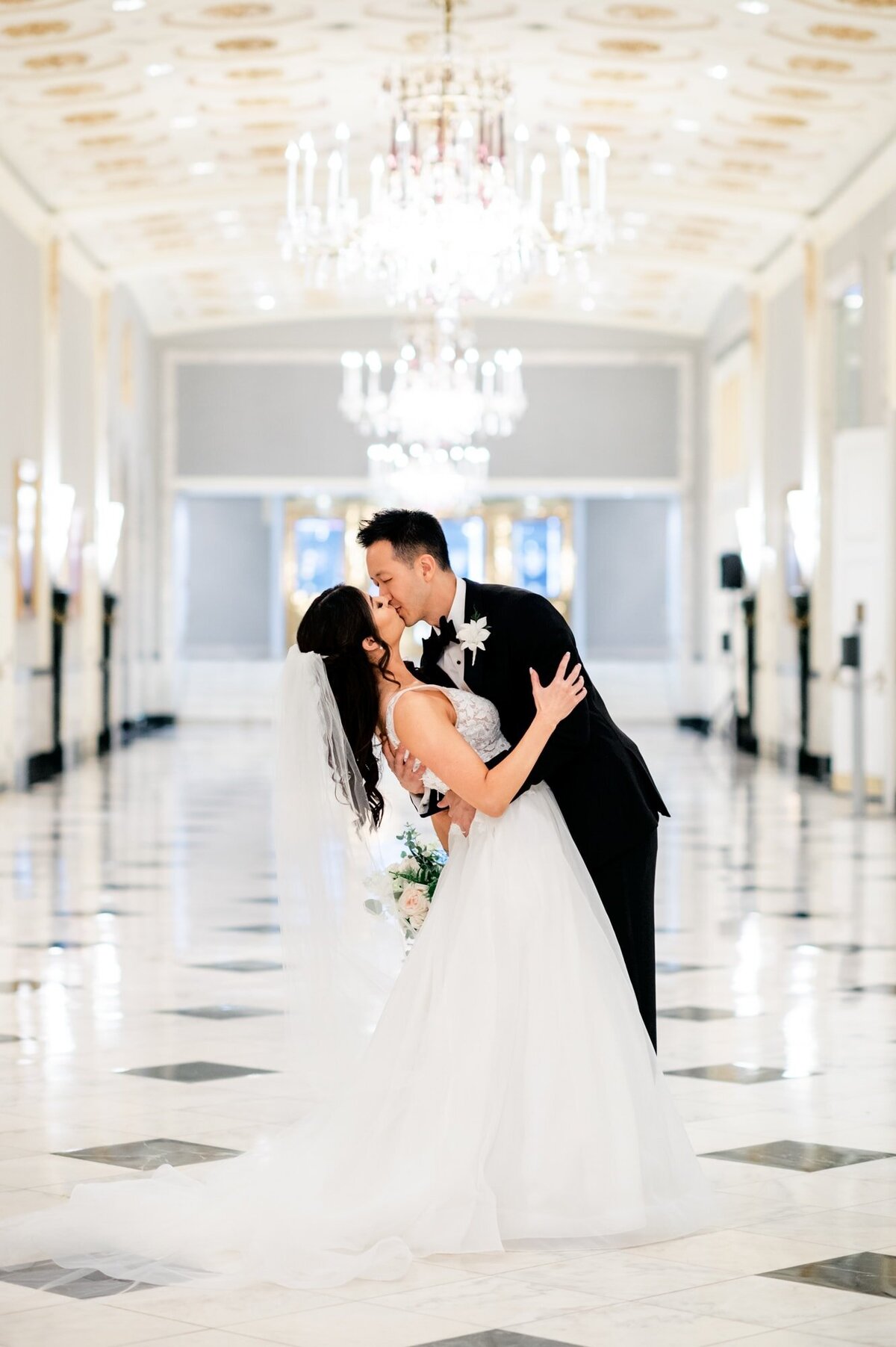 Wedding at The Mayflower Hotel in Washington DC Groom kissing Bride while he dips her in the historic hallway