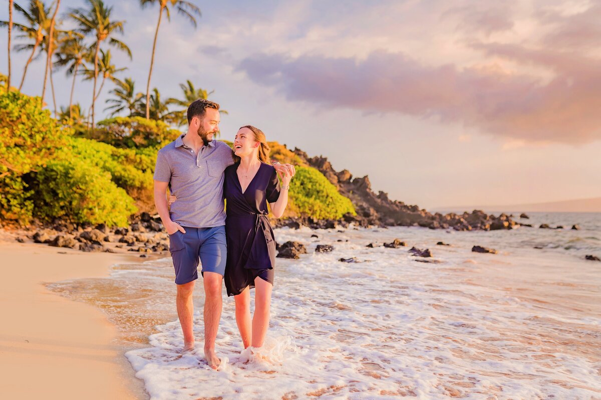 Couple strolls down the beach in Maui together at sunset