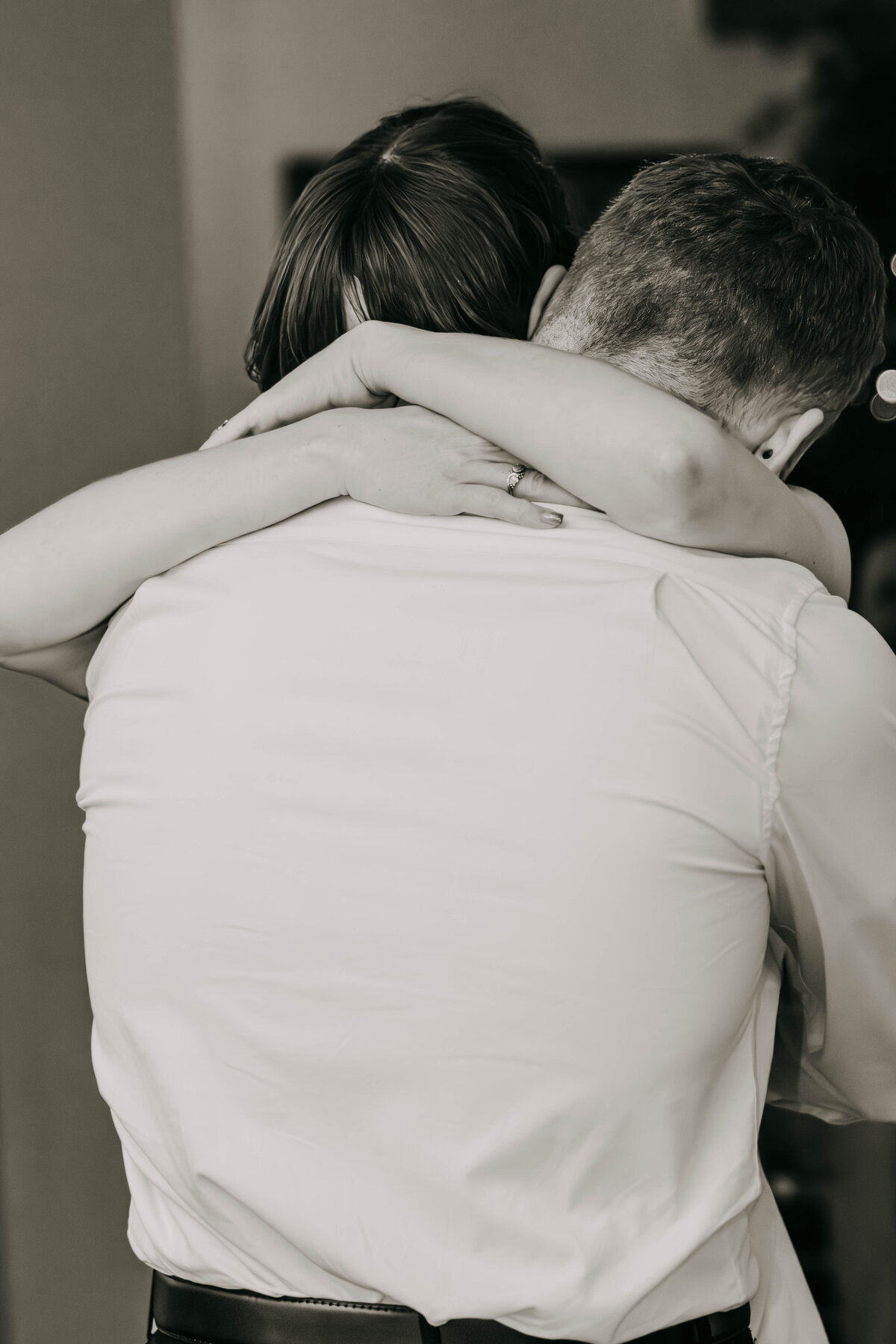 Black and white shot of bride and groom embracing during their first dance, capturing a tender, intimate moment.