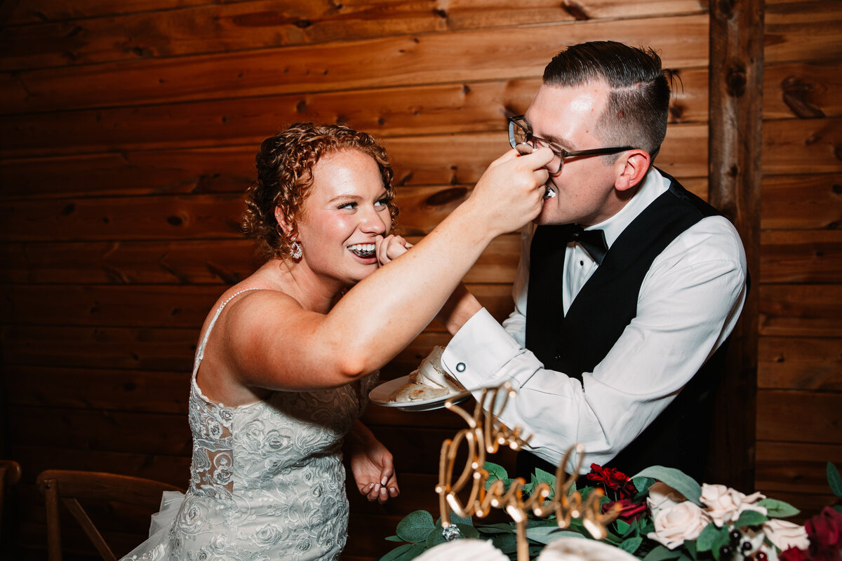 Newlyweds feed each other cake while laughing