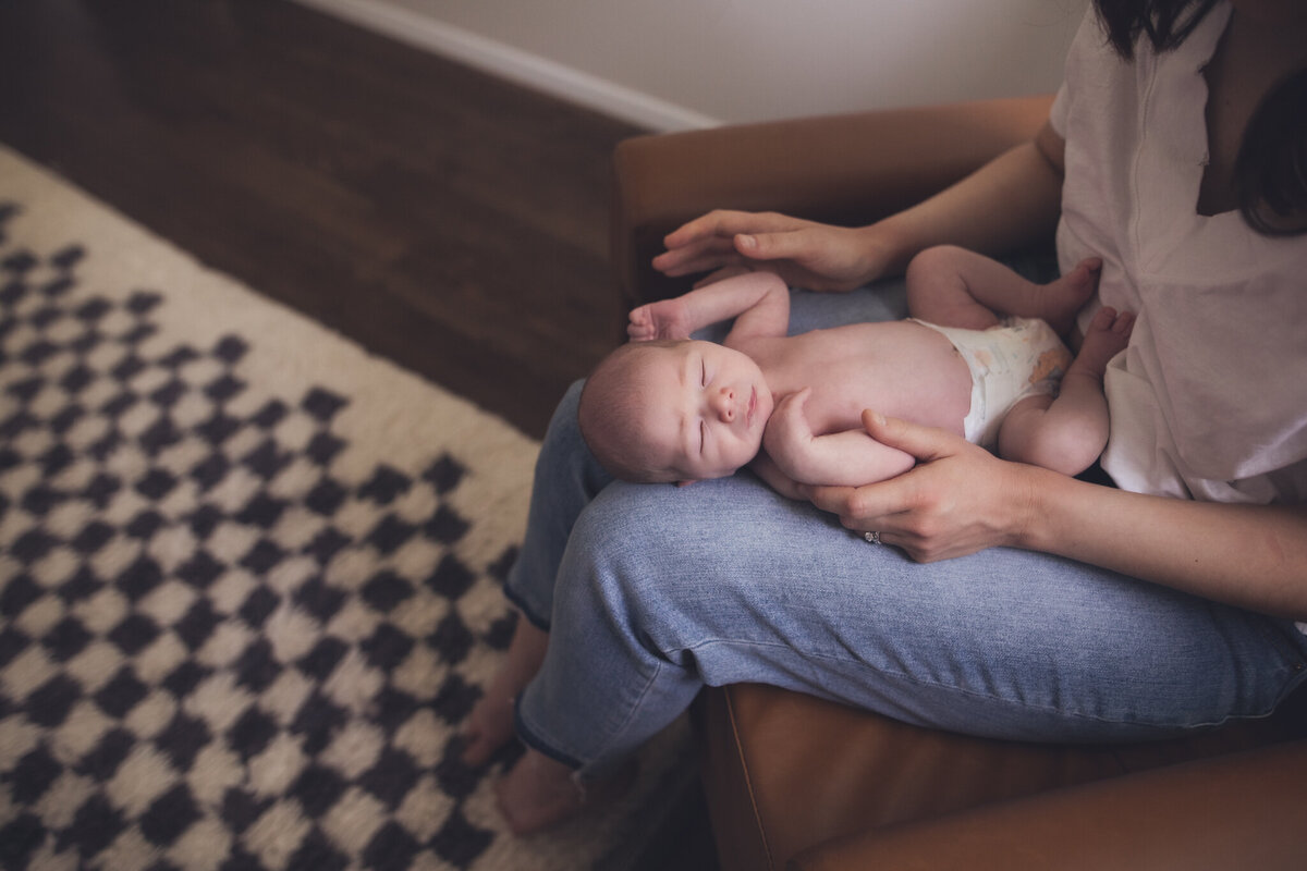 tiny newborn snuggled on moms lap