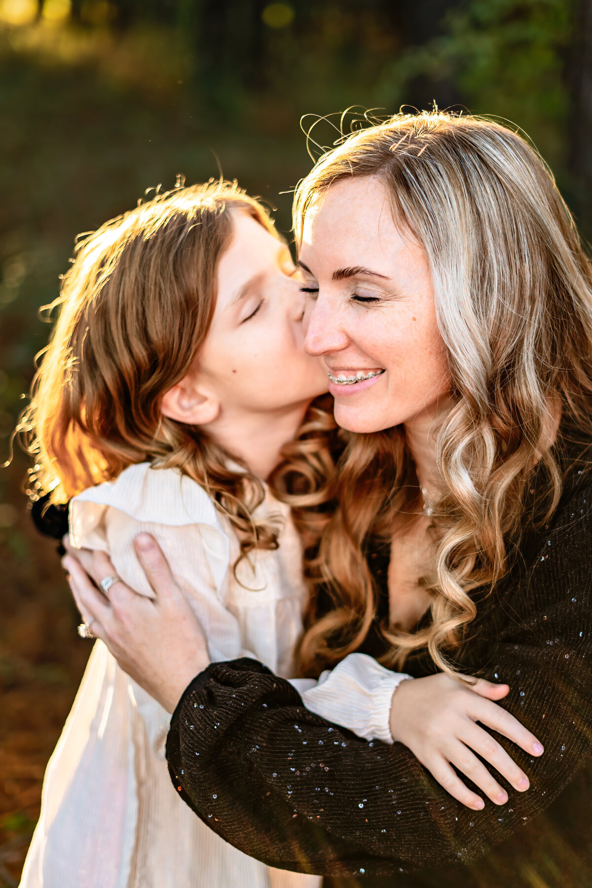 Daughter kissing mother on the cheek at sunset