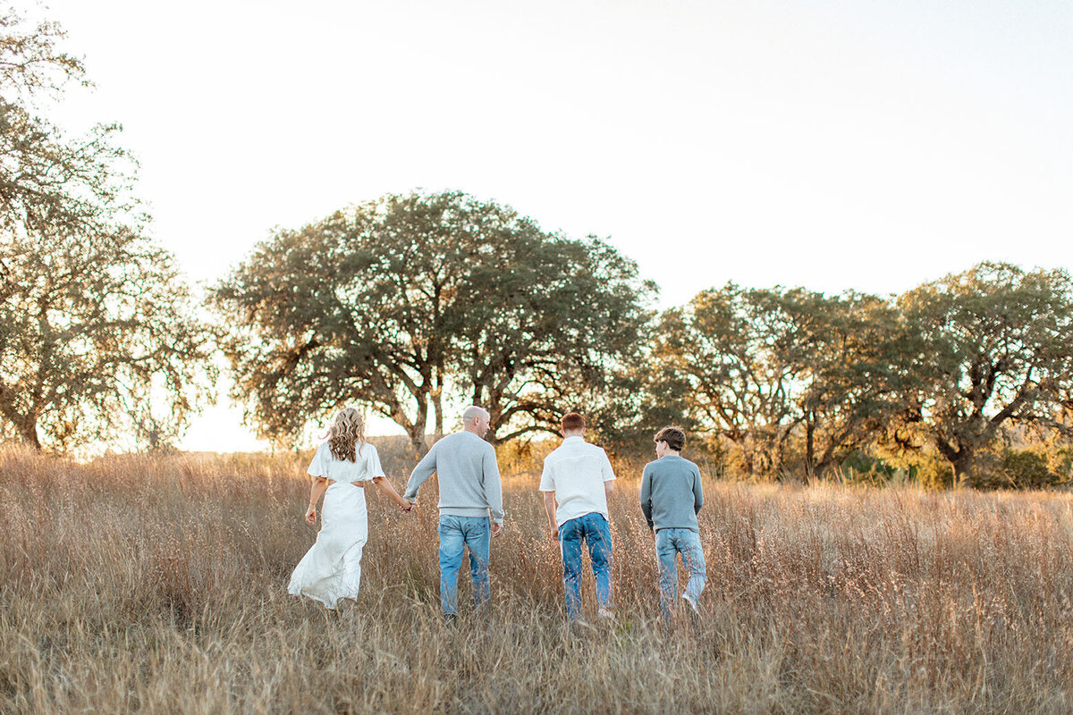 Family enjoying a sunlit field during a portrait session, photographed by Sara James in San Antonio.