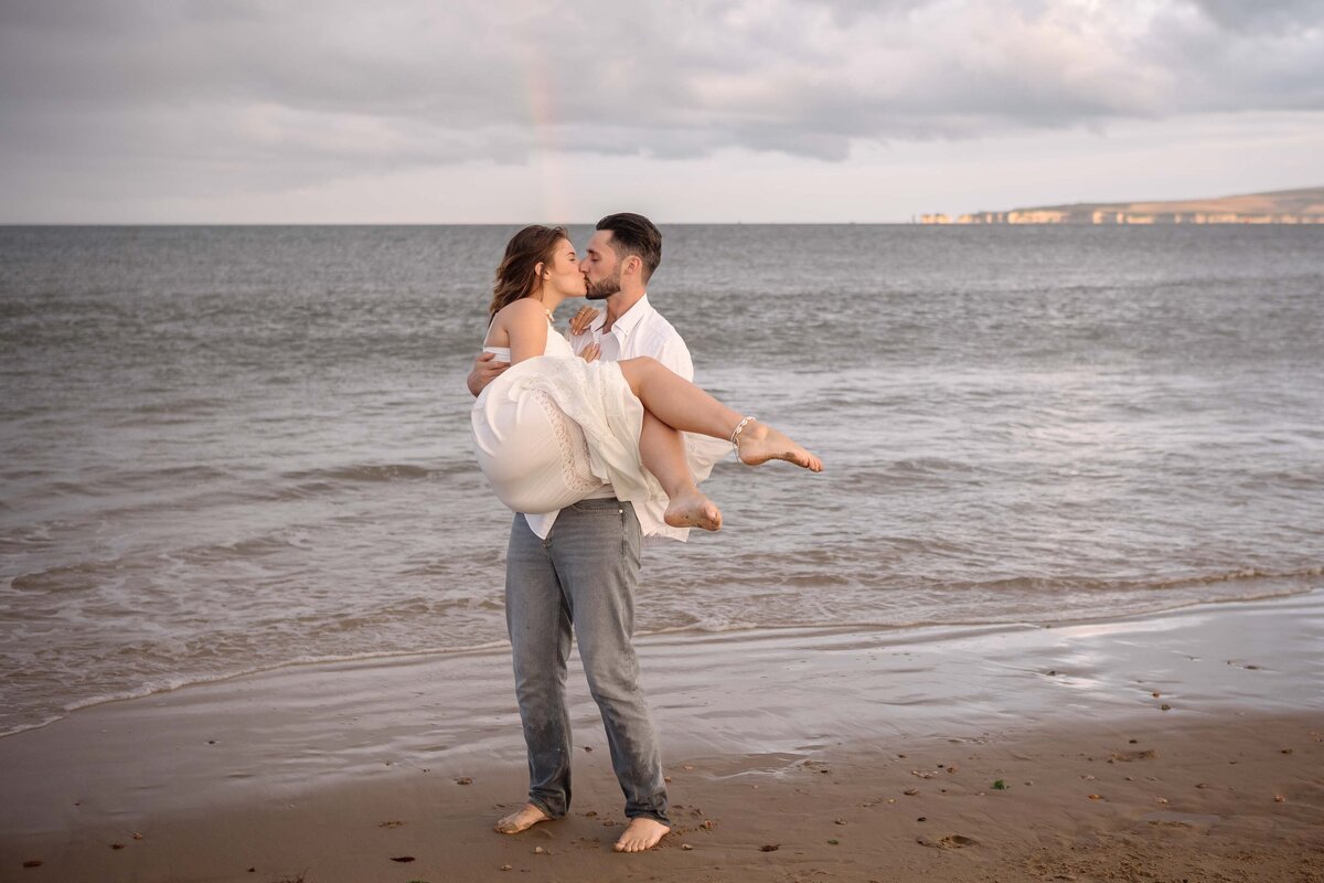 Boyfriend holding his girlfriend on the beach near the sea