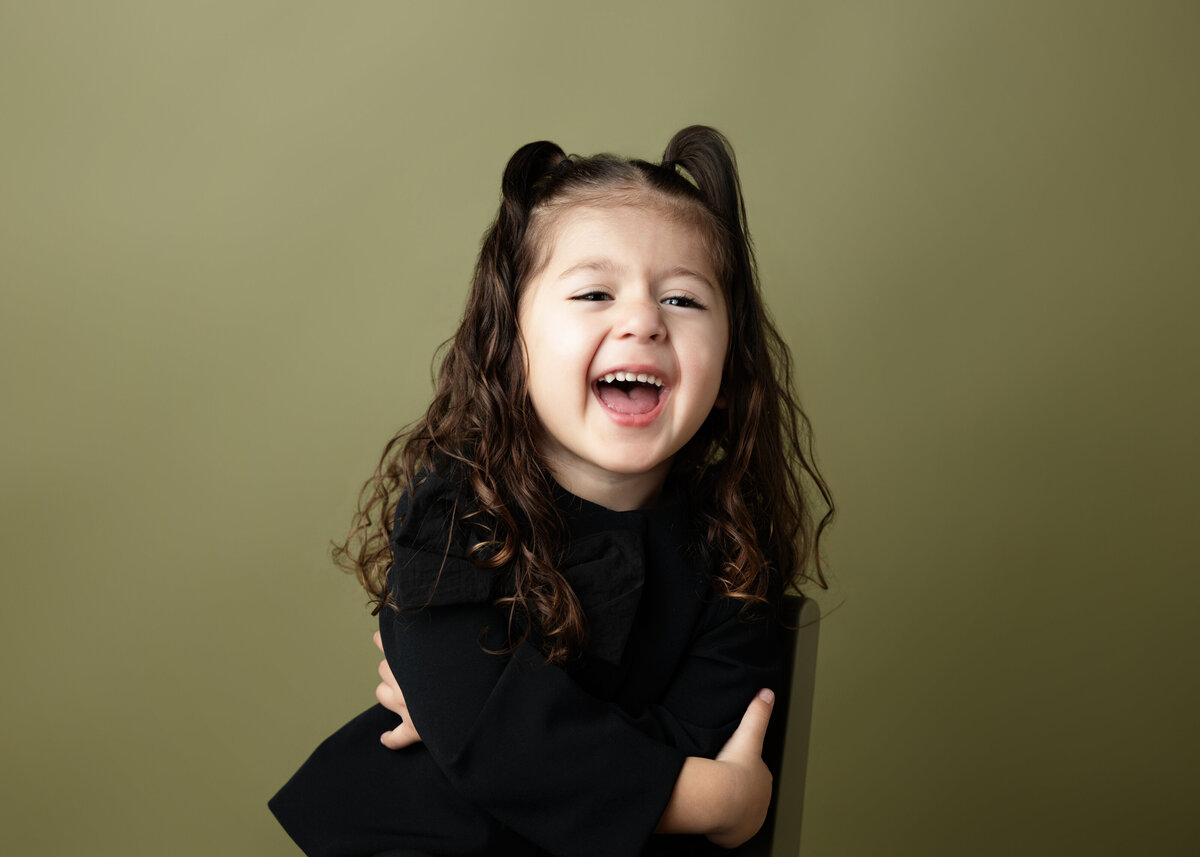 3 year old girl on olive green backdrop personality portraits children's milestone session at newport news virginia studio.