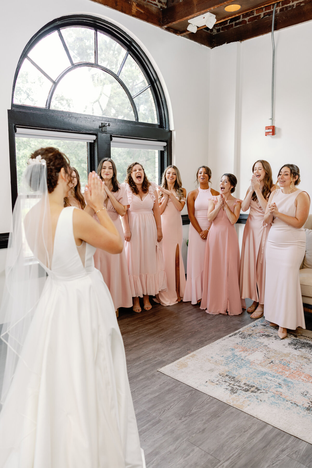 Bride and bridesmaids sharing tearful first look moment, Market Hall Raleigh NC