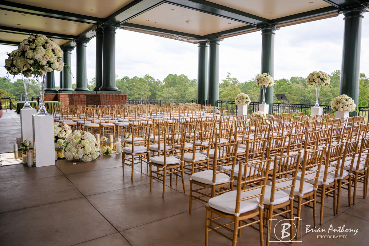 Elegant outdoor wedding ceremony setup featuring gold chairs and a scenic backdrop.