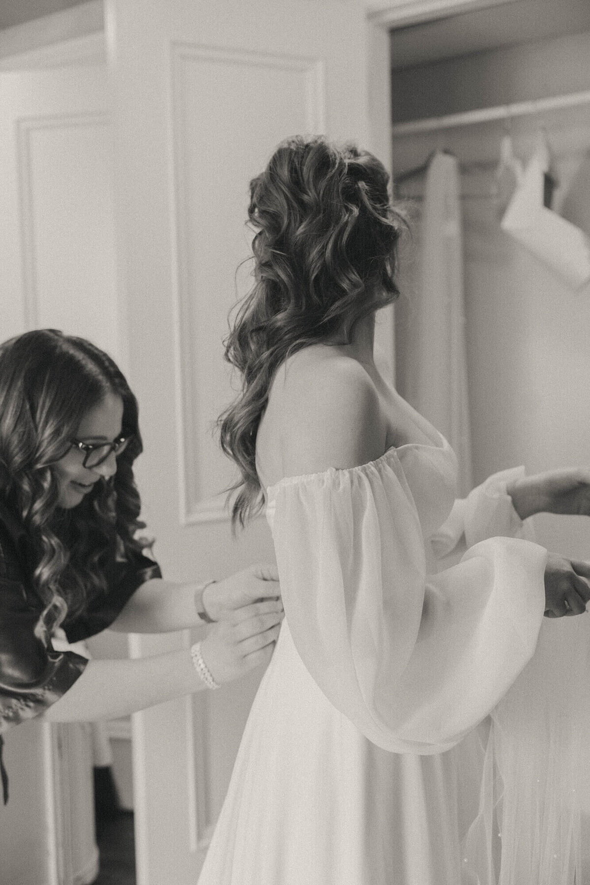 A bride getting her dress zipped up, representing the little moments she and her bridal party enjoy together.