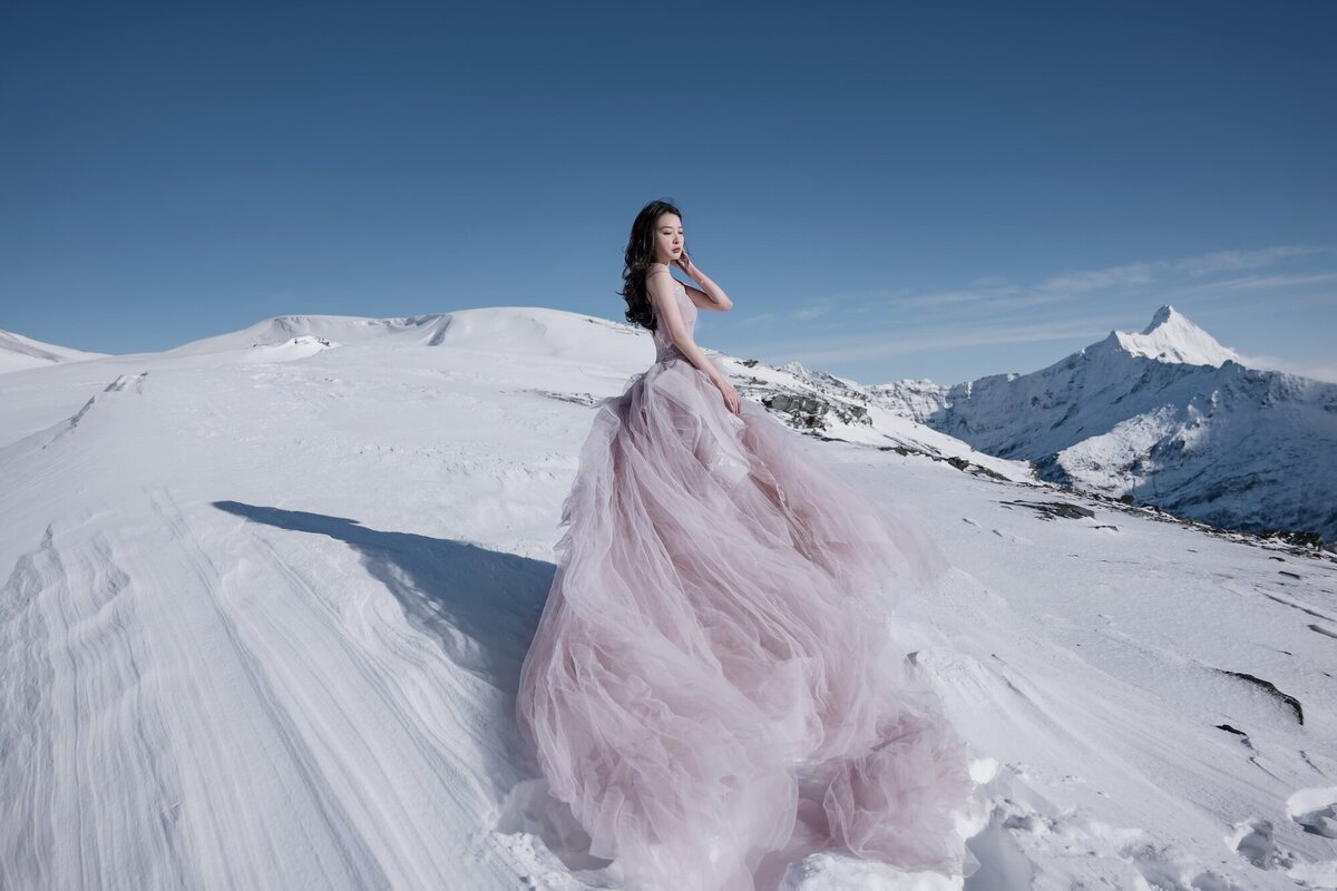 An editorial style shot of a woman in a couture dress on the snow at Dragonfly Peak.
