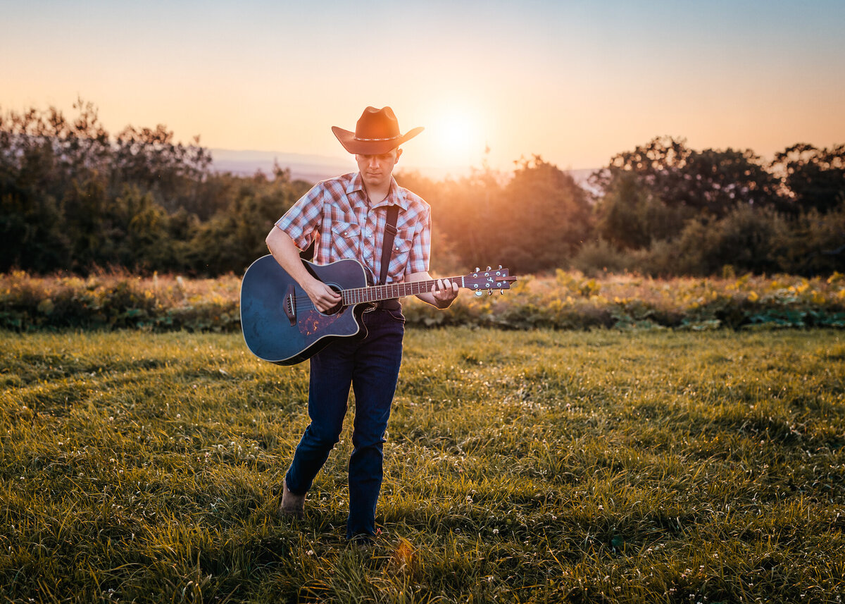 High School Senior playing guitar in field by Lisa Smith Photography
