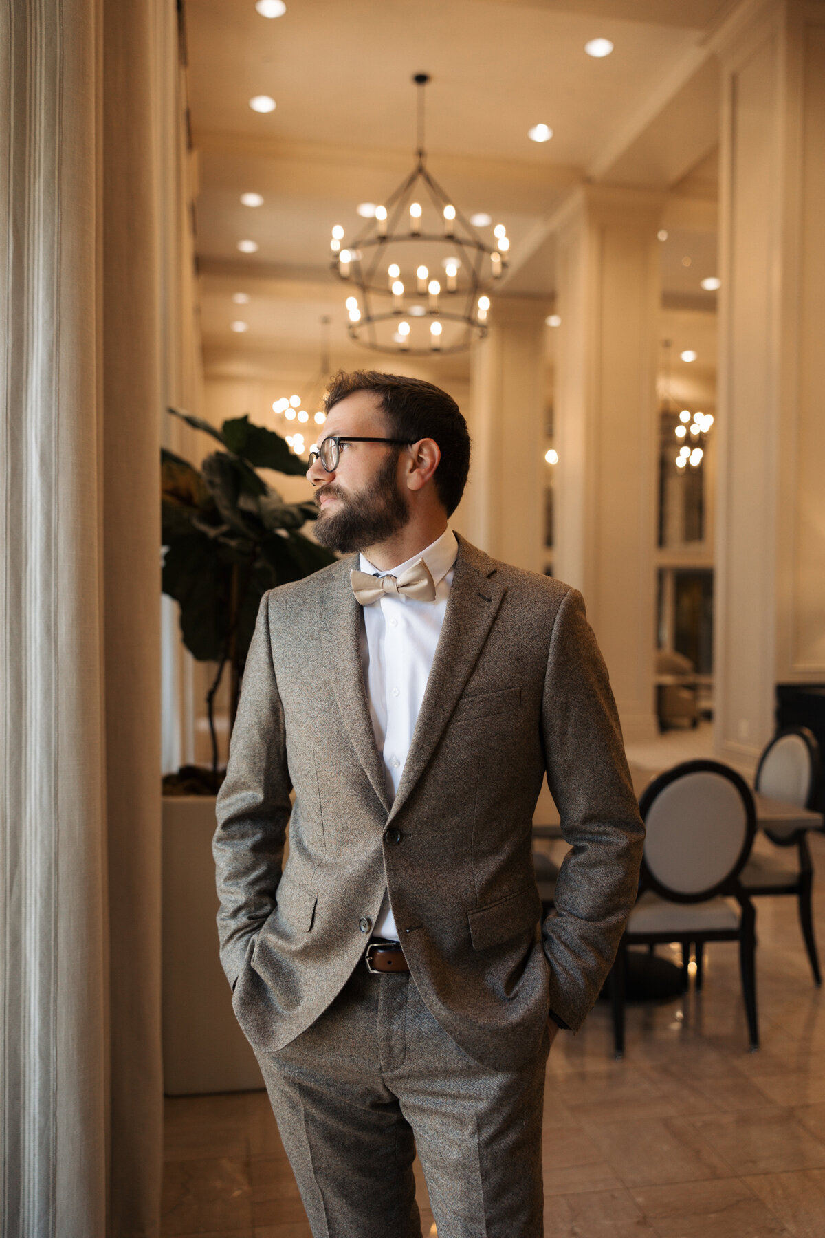 Groom’s portrait in warm indoor lighting at a historic venue.