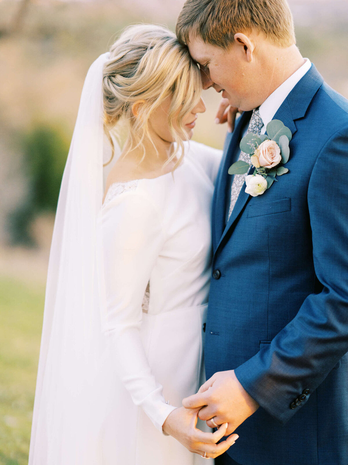 Bride and groom hold hands while embracing at Dripping Springs wedding