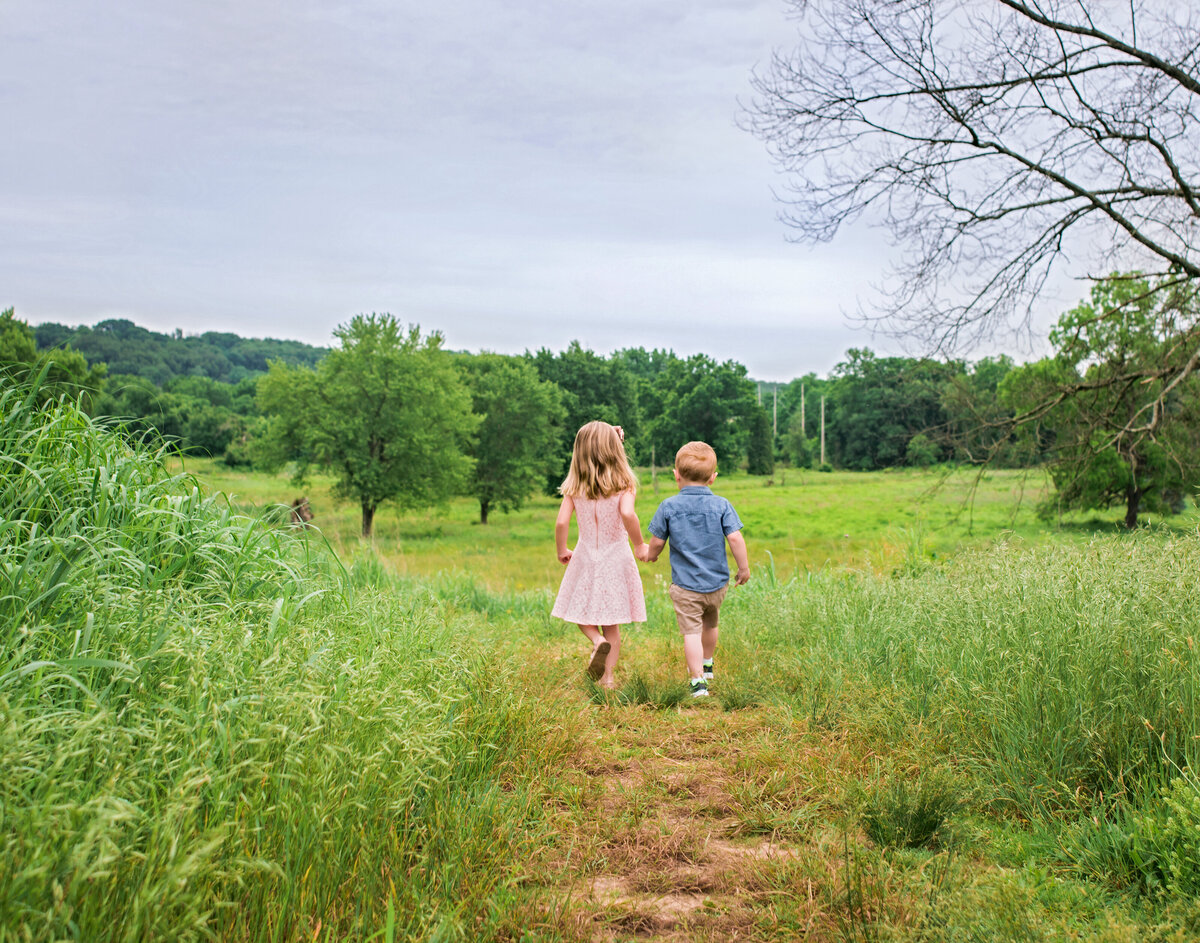 brother and sister walking on  a grassy trail
