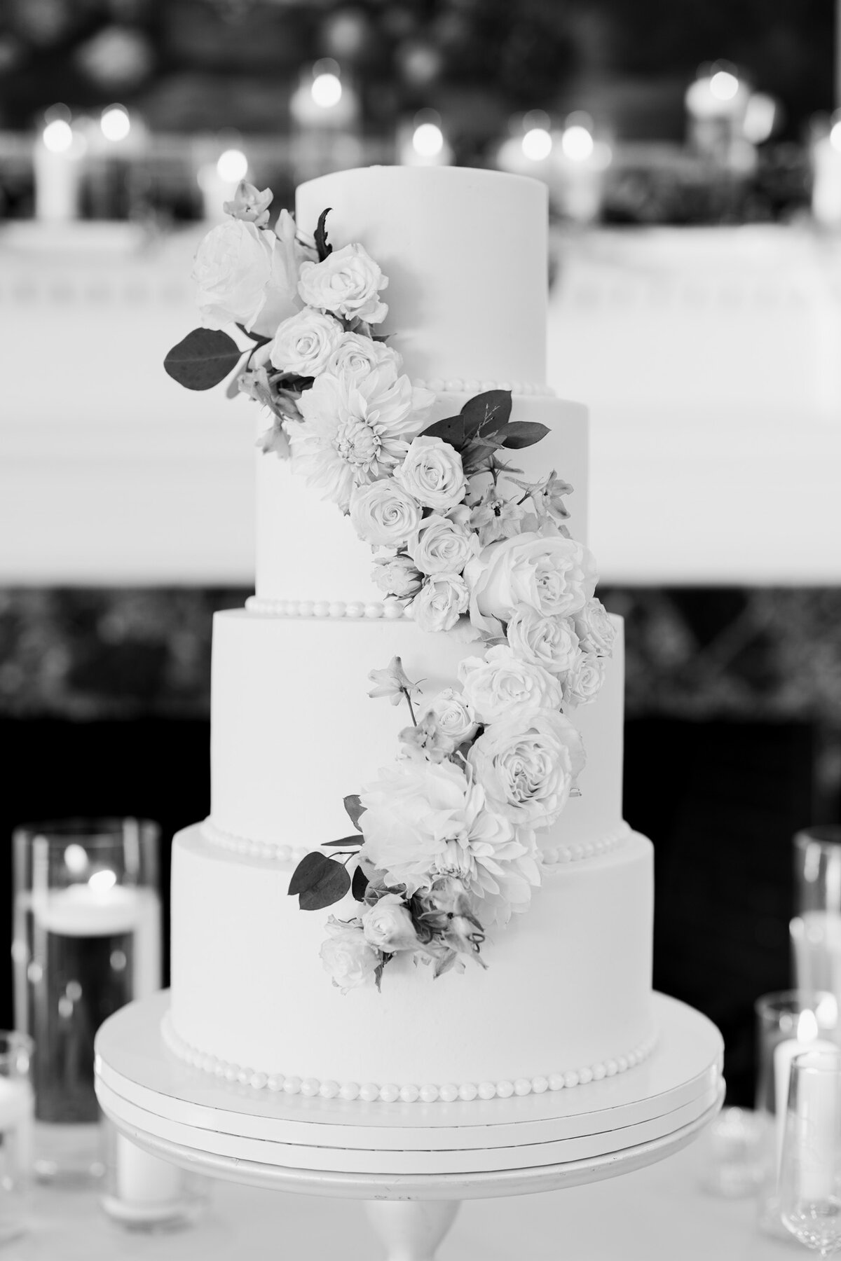A sophisticated black and white film photograph of an elegant tiered wedding cake during the reception at Gaston Country Club in Gastonia, North Carolina, beautifully documented by North Carolina wedding photographer Jessica Leigh Mason.