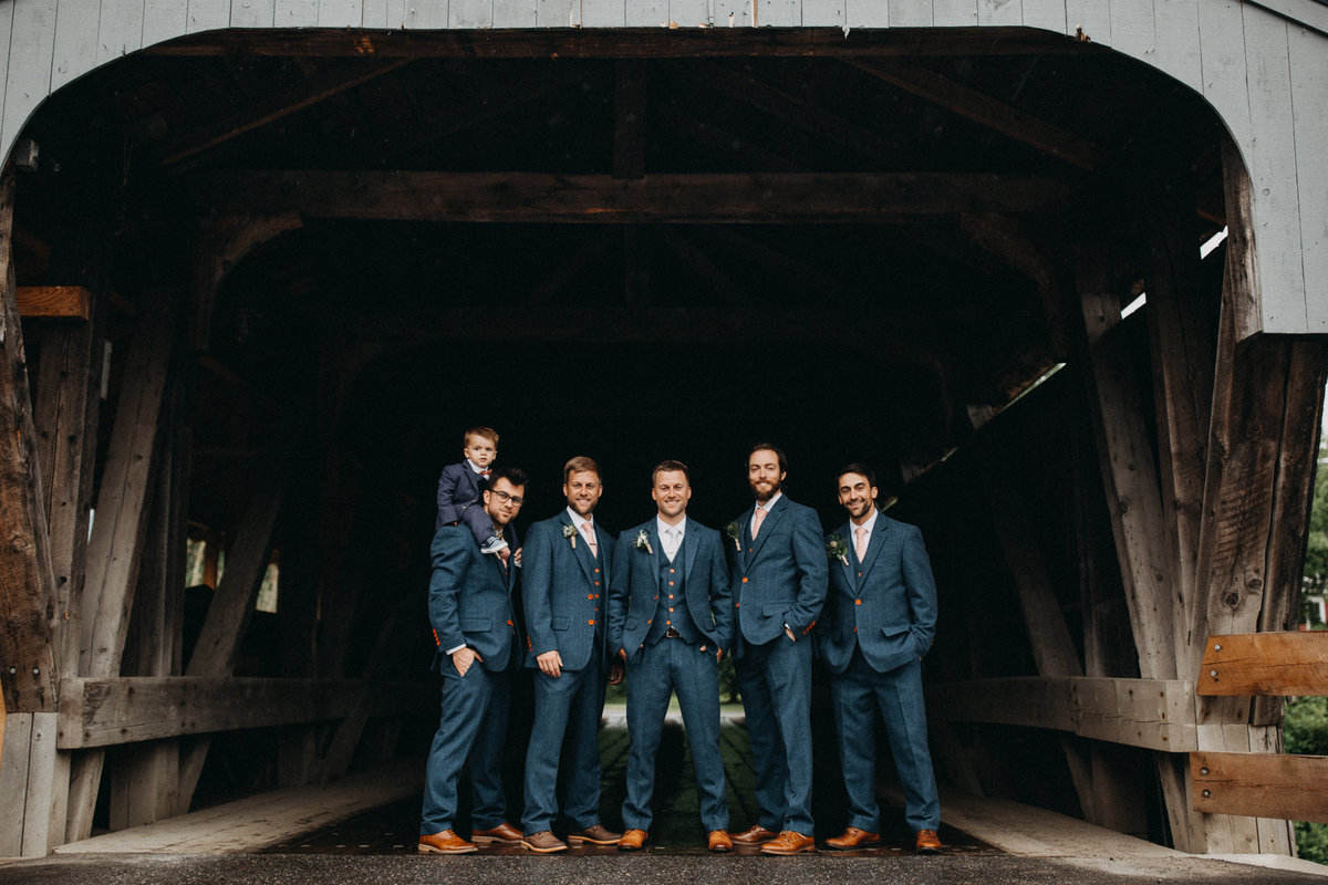 Groom and groomsmen under covered bridge