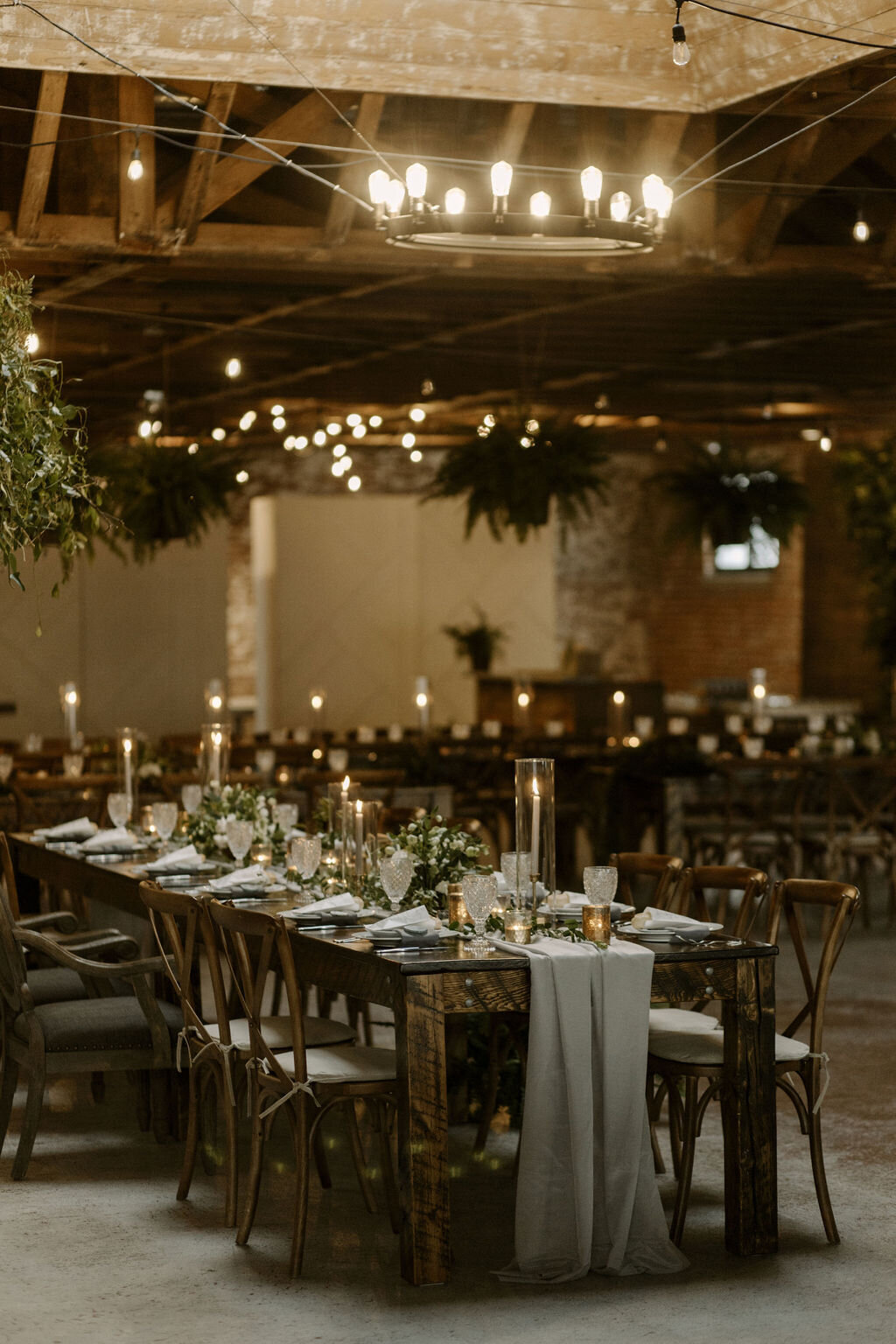 wedding reception table decor with gray napkins, candles and greenery